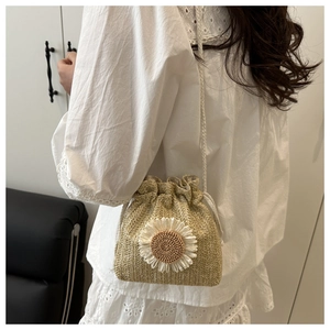 Detail view of woven bucket bag featuring a white daisy and drawstring closure strap