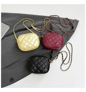 Close-up of quilted camera bags in gold, burgundy, and black with chain straps