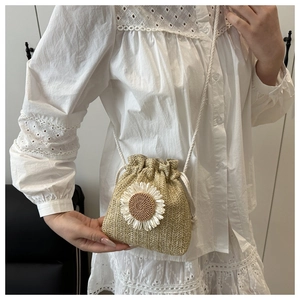 Detail of straw bucket bag featuring large sunflower decoration and drawstring closure