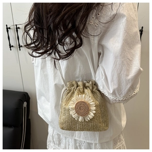 Detail view of woven straw bucket bag with 3D sunflower and white drawstring shoulder strap