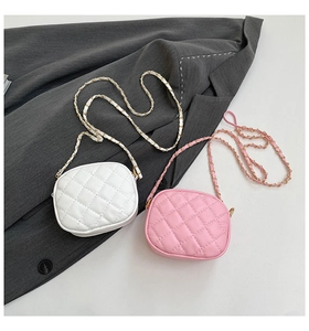 Detail of pink and white quilted crossbody bags with golden chain straps on a blazer