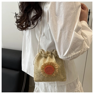 Detail of a straw bucket bag with sunflower decor and white drawstring shoulder strap