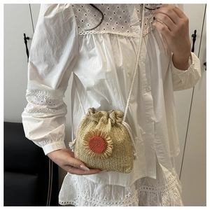 Detail of hand-woven straw bucket bag with sunflower applique and drawstring closure