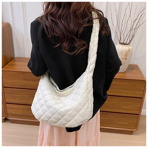 Détail d'un grand sac cabas blanc matelassé porté par un mannequin avec une texture souple