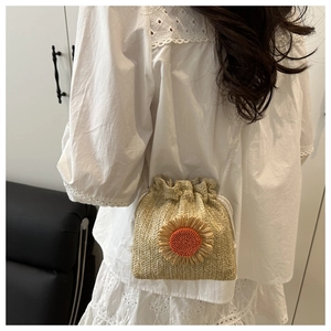 Detail of woven straw bucket bag with sunflower decor worn over a lace dress