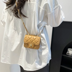 Mini sac matelassé jaune avec boucle pétale dorée porté sur une chemise blanche chic