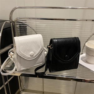 Minimalist quilted crossbody phone bags in black and white leather on a display shelf
