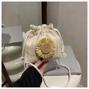 Detail of straw bucket bag with sunflower applique and white woven drawstring closure
