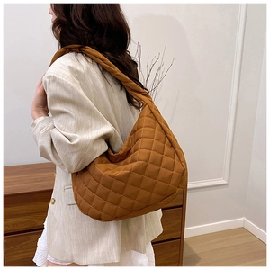 Sac fourre-tout matelassé marron porté par un mannequin dans un décor intérieur épuré