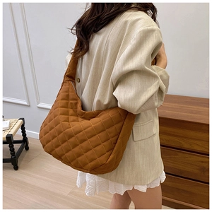 Gros plan d'un sac cabas marron matelassé avec surpiqûres en losanges porté par un mannequin