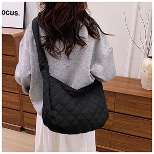 Détail du sac fourre-tout noir matelassé avec large bandoulière et grande capacité