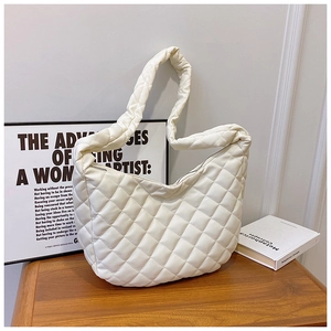 Détail du sac croissant matelassé blanc montrant sa texture douce sur une table en bois