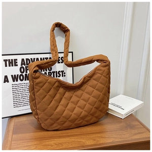 Détail macro du sac cabas matelassé marron avec motif losange et fermeture éclair métallique