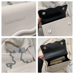 Detail der cremefarbenen Tasche mit Wellenkanten, Silberlogo und Magnetverschluss