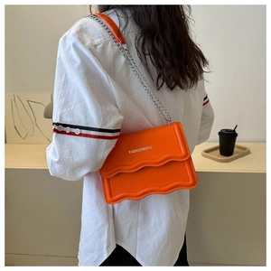 Detail der orangefarbenen Umhängetasche mit Wellenkante, Silberkette und Print-Logo