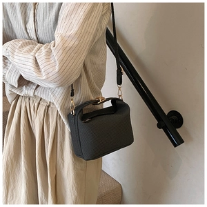 Detail van grijze crossbodytas met textuur, goudkleurige draaisluiting en smalle riem