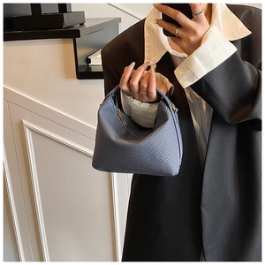 Detail of blue textured woven bucket bag with metal zipper and minimalist handle
