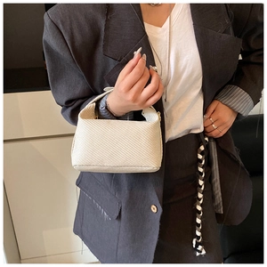 Detail view of a cream hobo bag with textured vertical stripes on a model's shoulder