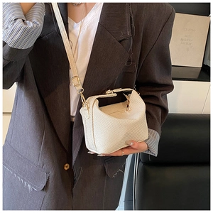 Detail of off-white woven texture handbag with golden clasp and adjustable strap