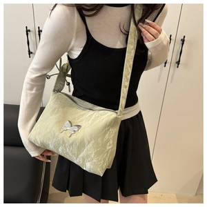 Dettaglio della borsa tote plissettata verde pallido con farfalla d'argento e tracolla