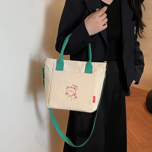 Chic beige canvas bucket bag with green handles and cartoon bear print for women