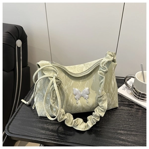 Dettaglio borsa baguette verde chiaro arricciata con farfalla d'argento e tracolla a balze