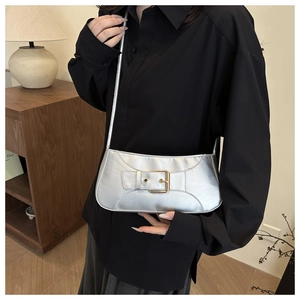 Detail of silver metallic underarm bag with a wide decorative metal buckle strap