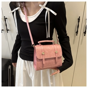 Sac à bandoulière en similicuir rose avec boucles dorées porté par un mannequin