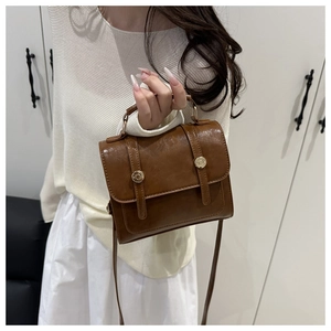 Vue détaillée du sac bandoulière rétro en cuir marron foncé avec boucles