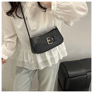 Chic black shoulder bag featuring a prominent gold square buckle on a model's outfit