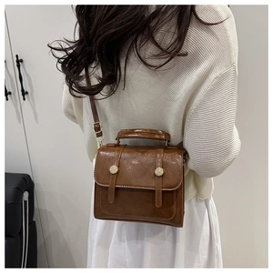 Vue latérale d'un sac carré en cuir marron vintage porté par un mannequin en intérieur