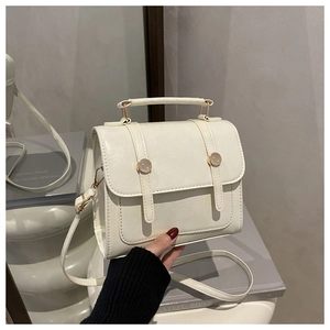 Détail d'un sac à bandoulière crème rétro avec boucles dorées et texture cuir naturel