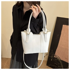 Detail of white PU leather bucket bag featuring gold metal rings and adjustable shoulder strap