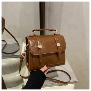 Détail d'un sac vintage marron caramel avec boucles à rivets dorés et fini brillant