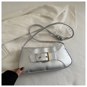 Detail of silver metallic baguette bag with bold gold buckle and knotted shoulder strap
