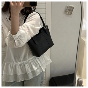 Classic black leather shoulder bag with gold hardware shown in a casual lifestyle setting