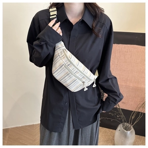 Detail of striped canvas chest bag featuring dual zippers and adjustable woven strap
