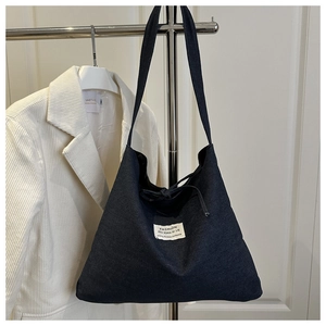 Detail of minimalist denim tote bag showing drawstring closure and woven brand label