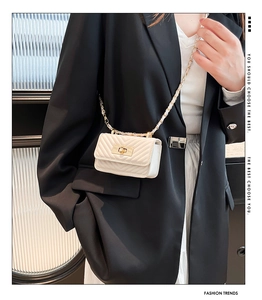 Close-up of cream mini bag with V-shaped quilting and gold-tone chain strap worn on black suit