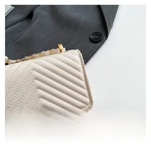 Close-up of off-white quilted leather bag with V-shaped stitching and gold chain strap