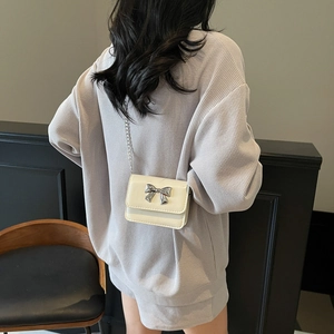 Elegant cream mini crossbody bag with silver bow accent and delicate chain strap