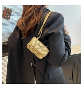 Detail of golden mini crossbody bag with V-shaped quilting and a gold metal twist lock