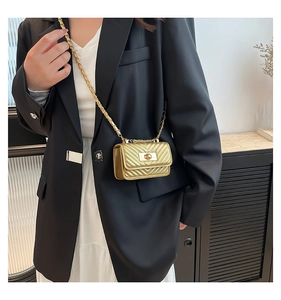 Macro detail of gold quilted mini crossbody bag with metal chain strap and twist lock