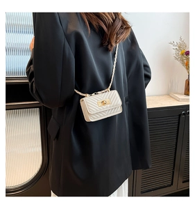 Mini white crossbody bag with V-quilted pattern and gold chain strap on a model