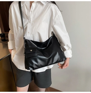 Detail of a minimalist black tote bag with a small hanging pouch and long shoulder straps