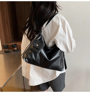Detail of black leather tote bag with silver chain and matching mini pouch accessory