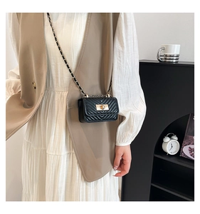 Close-up of black quilted mini crossbody bag with golden chain strap and twist lock