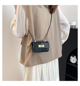 Detail of black chevron quilted crossbody bag with gold-tone twist lock and chain strap