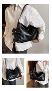 Close-up of black glossy leather tote bag with metallic chain and small coin pouch detail