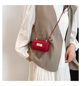 Detail of red quilted mini crossbody bag with gold chain strap and turn-lock closure